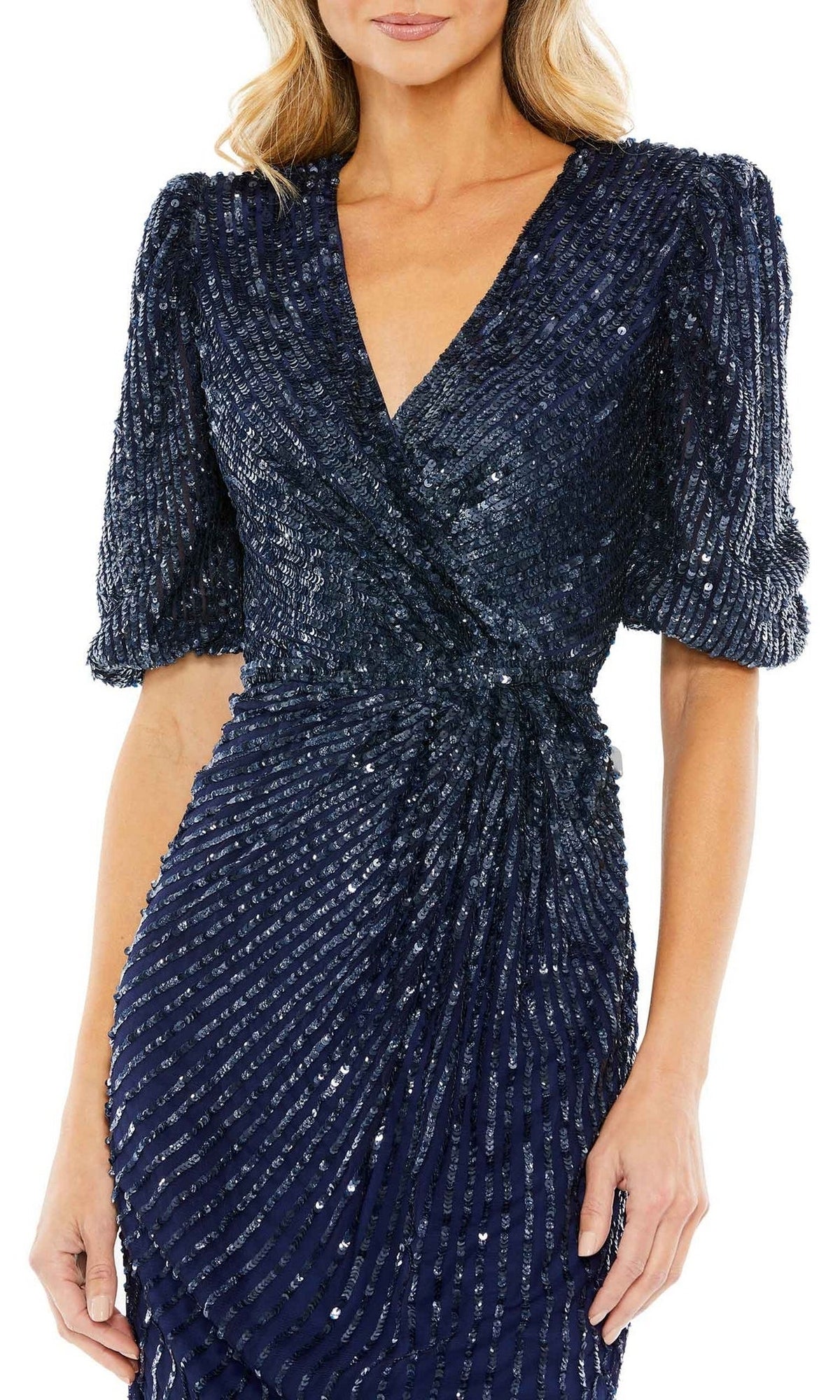 A woman wears the Short Semi-Formal Dress 5578 by Mac Duggal—midnight blue with sequins, short puff sleeves, a v-neckline, and a wrap-style bodice.